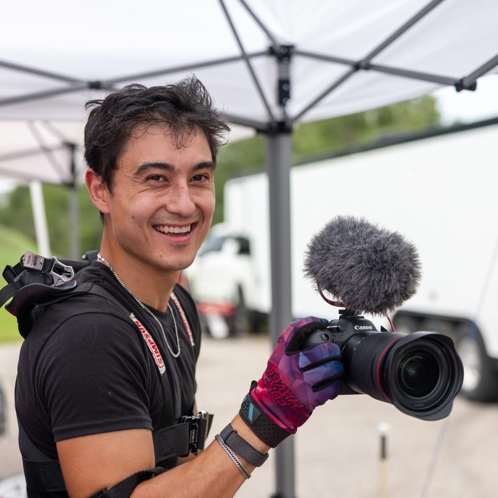 Zach Chin smiling with his camera in the paddock