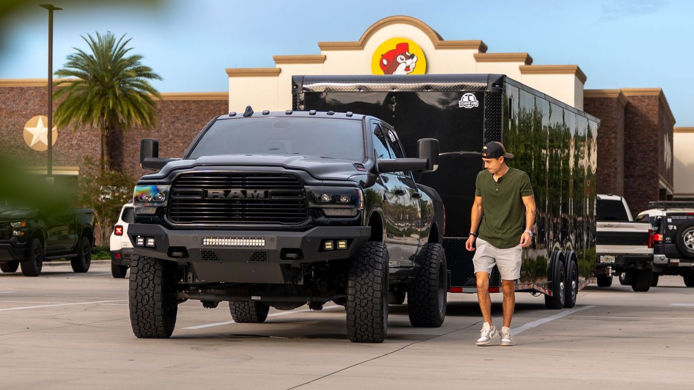 Zach walking beside his black 2020 Ram 2500 towing an enclosed trailer